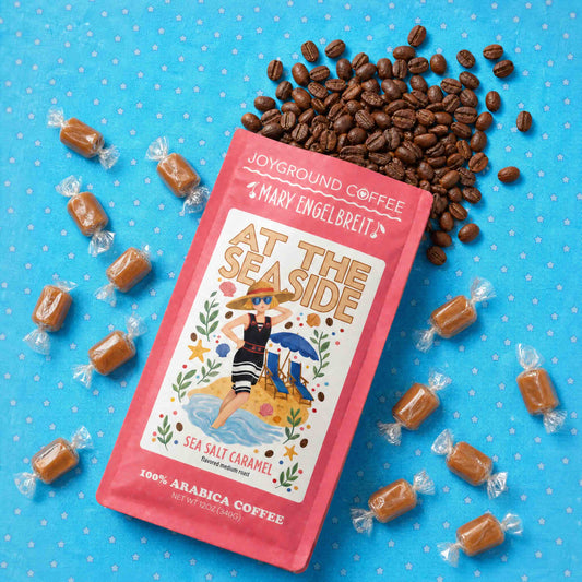 Joyground Coffee Mary Engelbreit At the Seaside package with sea salt caramel candies and coffee beans on a blue background