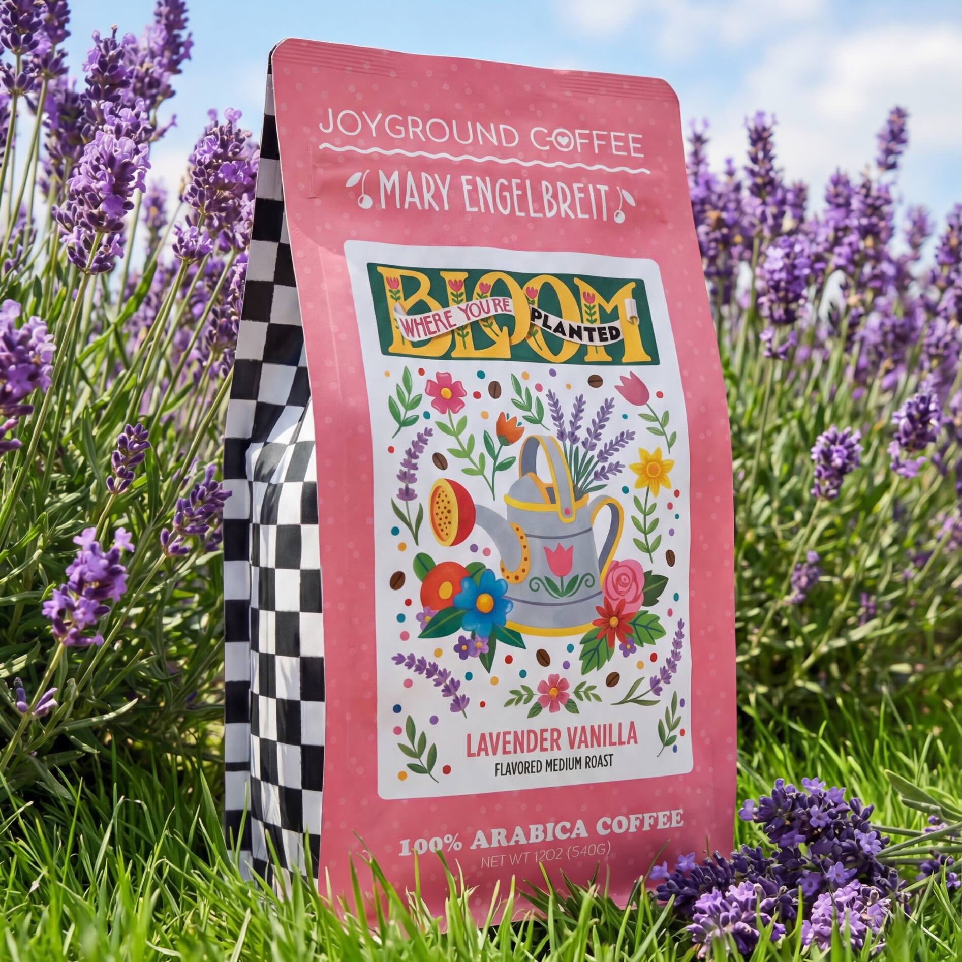 Mary Engelbreit Bloom Where You're Planted Lavender Vanilla coffee bag in a field of lavender