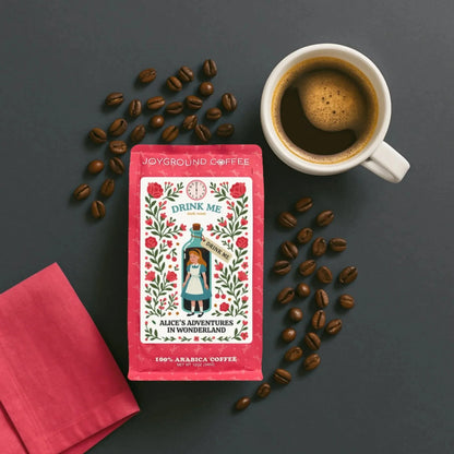 Alice in Wonderland Dark Roast coffee bag with coffee mug, coffee beans, and pink napkin