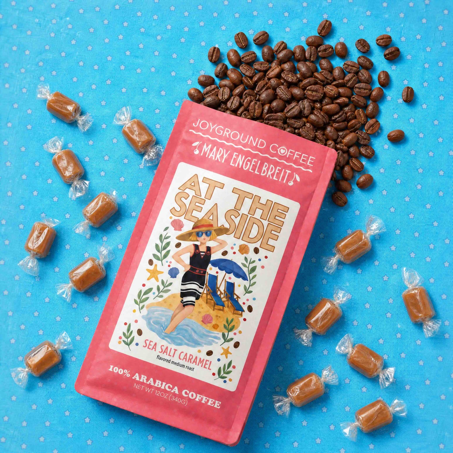 Joyground Coffee Mary Engelbreit At the Seaside package with sea salt caramel candies and coffee beans on a blue background