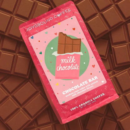 Chocolate Bar Joyground Coffee pink coffee bag placed on top of milk chocolate candy bar pieces.