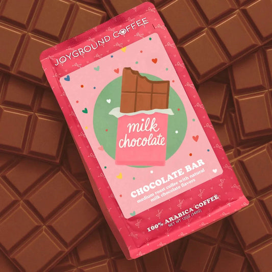 Chocolate Bar Joyground Coffee pink coffee bag placed on top of milk chocolate candy bar pieces.