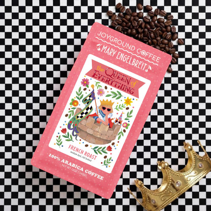Joyground Coffee x Mary Engelbreit "The Queen of Everything" French Roast coffee bag flat lay on black and white checkered background with gold crown.