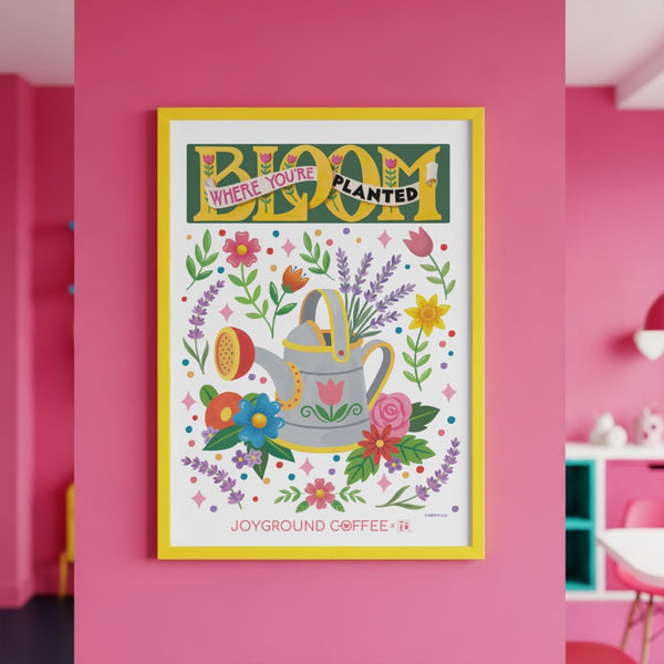 Framed Mary Engelbreit Bloom Where You're Planted art print from Joyground Coffee on a pink wall.