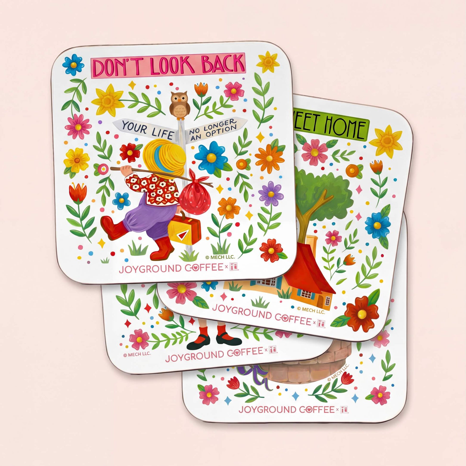 Four white illustrated Joyground Coffee x Mary Engelbreit coasters on a light pink background