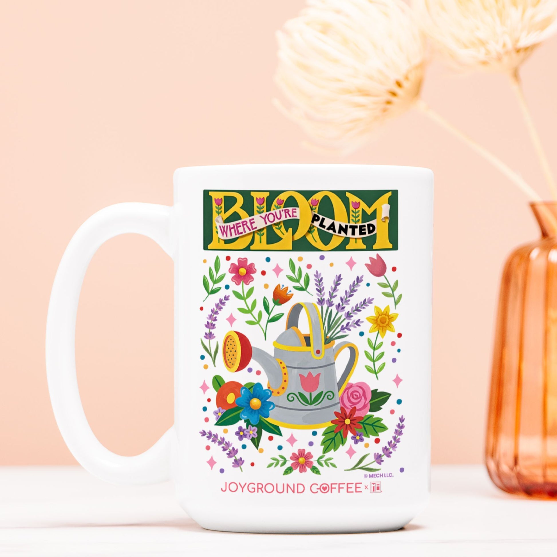 Mary Engelbreit Bloom Where You're Planted 15oz mug by Joyground Coffee on a peach background