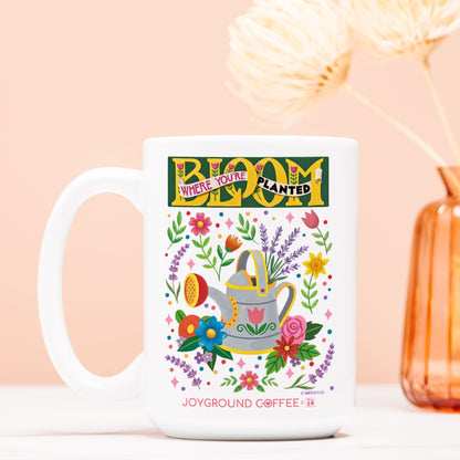 Mary Engelbreit Bloom Where You're Planted 15oz mug by Joyground Coffee on a peach background
